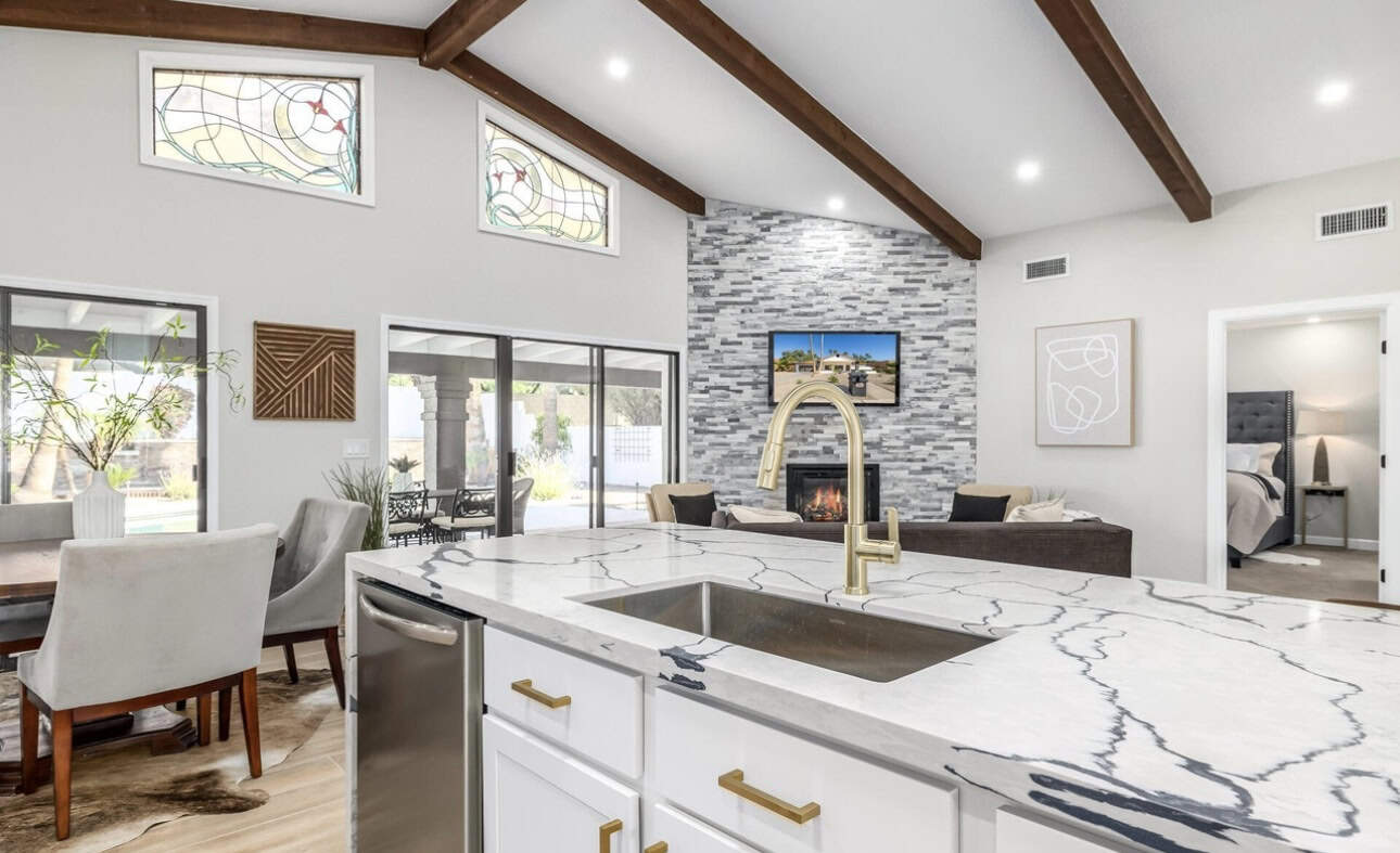 Bright modern kitchen with stone feature wall, large windows, and open living area.