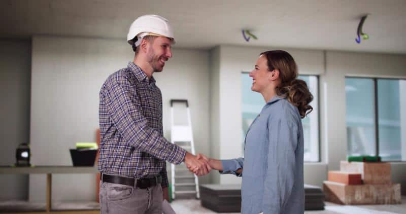 Home renovation consultation with a contractor and client shaking hands.