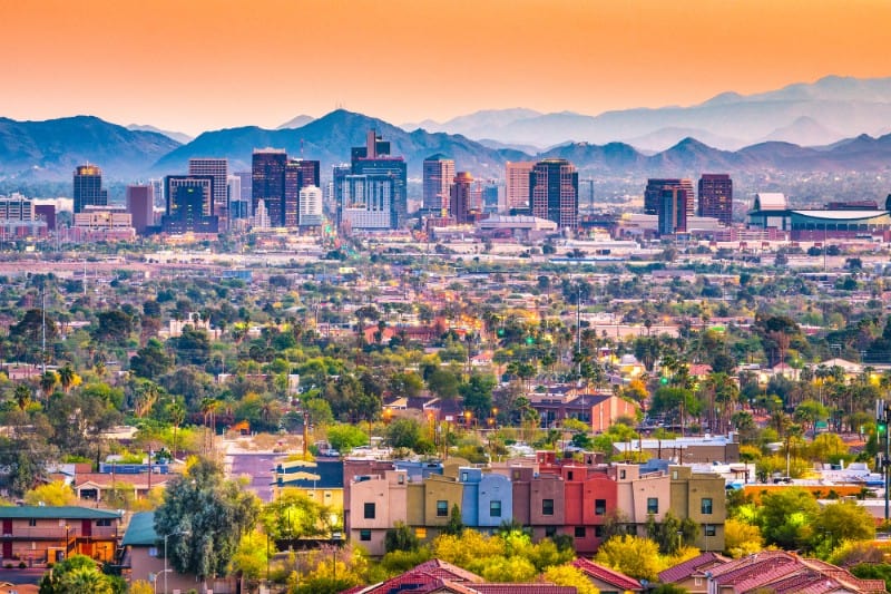 Los Angeles skyline with skyscrapers and mountains at sunset.
