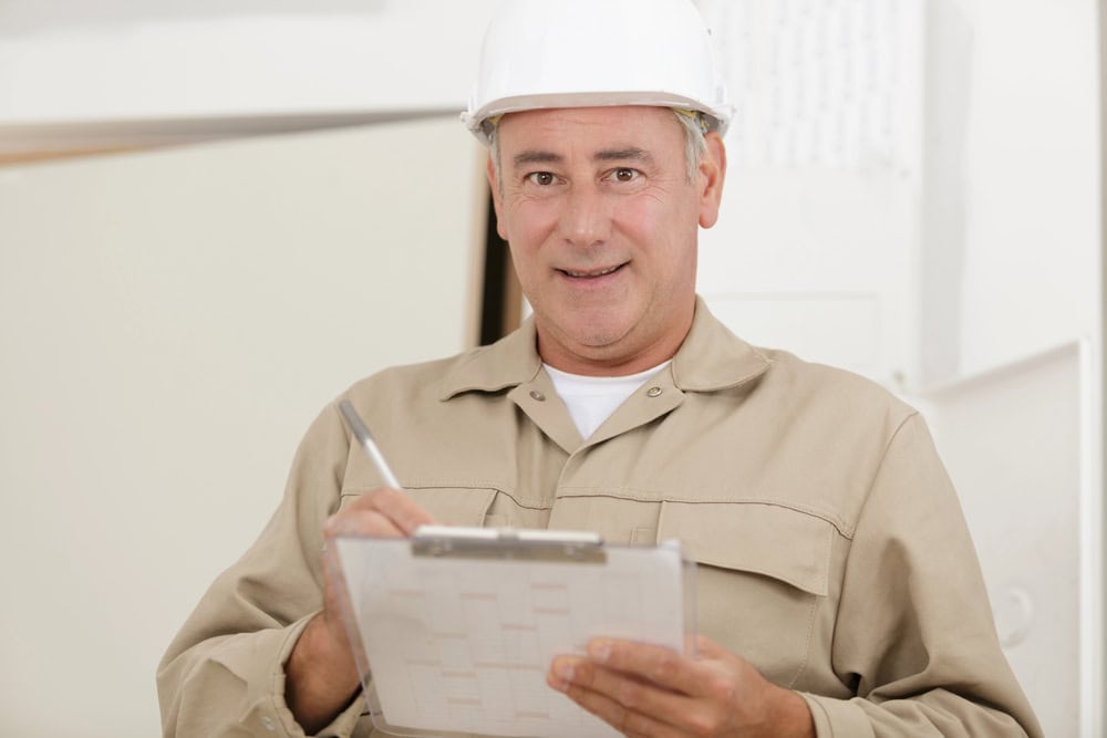 Construction worker with clipboard and safety helmet.